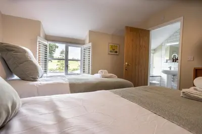 a bedroom with two beds and a window at Hen Llwyn by Birch Stays New Home in Llangadwaladr
