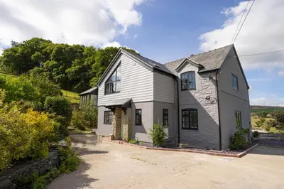 a white and black house with a driveway at Hen Llwyn by Birch Stays New Home in Llangadwaladr