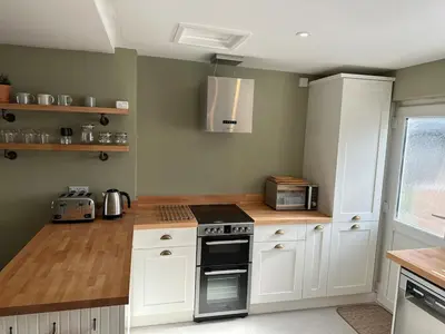 a kitchen with white cabinets and a stove top oven at Bear cottage in Brecon