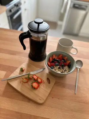 a cup of coffee and a bowl of strawberries on a table at Bear cottage in Brecon