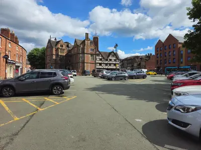 a parking lot with cars parked in front of buildings at The Loft - a stylish 2-bed in prime central location - Pass the Keys in Shrewsbury