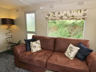 a brown couch in a living room with a window at Gwybedog in Llanwrda