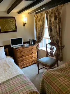 a bedroom with two beds and a desk with a television at Borderers Inn in Brecon