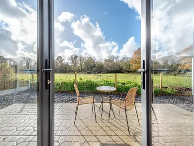 a patio with a table and chairs and a view of a field at Cwtch Honey - Uk49792 in Cribyn