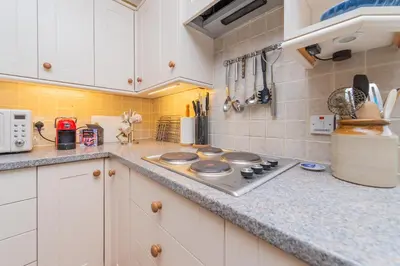 a kitchen with white cabinets and a stove top oven at Pear Tree Cottage in Shrewsbury