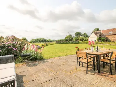 a patio with a table and chairs and a field at Pear Tree Cottage in Shrewsbury