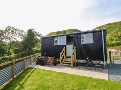 a black tiny house with a patio and grass at Charollais in Oswestry