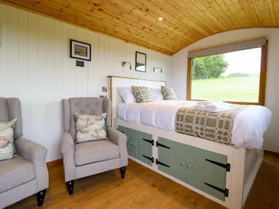 a bedroom with a bed and a window and two chairs at Defaid Cymreig in Oswestry