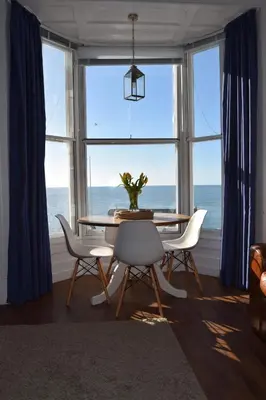 a dining room with a table and chairs in front of a window at Awel Mor 3 Luxury Apartment in Aberystwyth