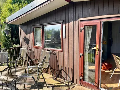 a group of chairs sitting on the deck of a cabin at Robins' Rest - 22 Caer Beris Luxury Lodge Park NEW Sleeps 6 Riverside Reteat in Builth Wells