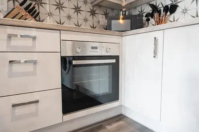 a kitchen with white cabinets and an oven at Mermaids Hideaway in Aberaeron