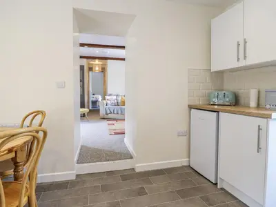 a kitchen with white cabinets and a living room at 1 Y Llew in Llandinam