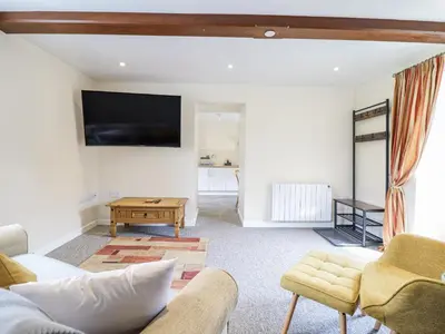 a living room with a couch and a tv on the wall at 1 Y Llew in Llandinam