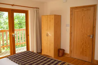 a bedroom with a bed and a wooden cabinet at Owls Roost Eco Lodge Apartment Lampeter in Lampeter