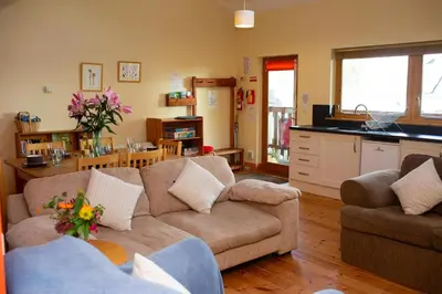 a living room with two couches and a kitchen at Robins Perch Eco Lodge Apartment Lampeter in Lampeter
