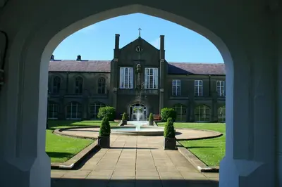an archway leading to a large building with a fountain at Robins Perch Eco Lodge Apartment Lampeter in Lampeter