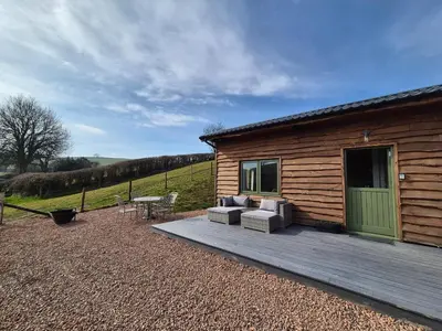 a cabin with a wooden deck with a couch and a table at Birch Banc Retreats - Bedw Cabin