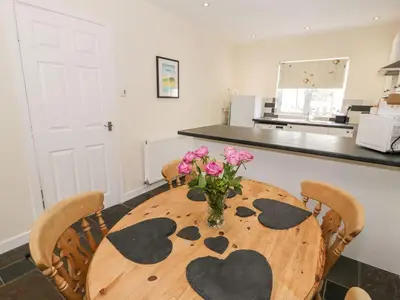 a dining room table with a vase of flowers on it at 3 Riverside Bungalows in Llanbedr