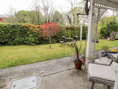 a patio with a table and chairs and a yard at 3 Riverside Bungalows in Llanbedr