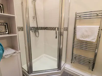 a shower with a glass door in a bathroom at 3 Riverside Bungalows in Llanbedr