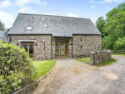 an old stone house with a gravel driveway at Wern Farm Barn in Cwmdu