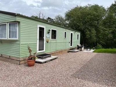 a green trailer with a patio and a house at Sylvan in Builth Wells