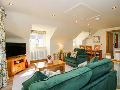 a living room with green furniture and a flat screen tv at The Hideaway in Shrewsbury