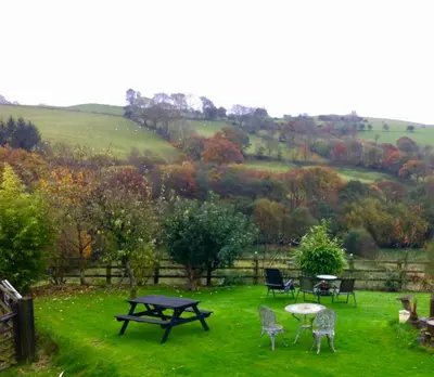a group of tables and chairs in a field at Five Saints Farmhouse B&B in Pumpsaint