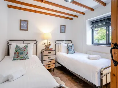 two beds in a room with white walls and wooden ceilings at The Old Cowsheds 5 - Llanilar - Uk49790 in Cribyn