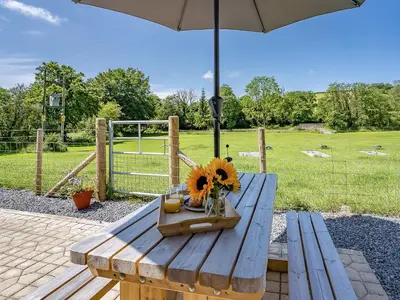 a picnic table with a vase of sunflowers and an umbrella at The Old Cowsheds 4 - Daniel Ddu - Uk49789 in Cribyn