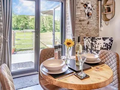 a dining room with a wooden table and a glass door at The Old Cowsheds 4 - Daniel Ddu - Uk49789 in Cribyn