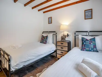 two beds in a room with white walls and wooden floors at The Old Cowsheds 4 - Daniel Ddu - Uk49789 in Cribyn