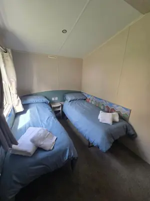 two beds in a room with blue pillows at 6 Birth Caravan Quay West Sea Views in New Quay