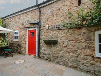 a red door on the side of a stone building at Little Barn in Oswestry