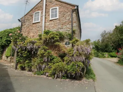 a stone house with flowers on the side of a road at Little Barn in Oswestry