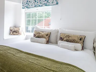a large white bed with pillows and a window at Fantastic 3-bed home close to Shrewsbury centre - Pass the Keys in Shrewsbury