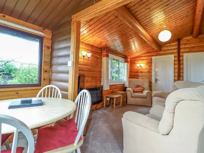 a log cabin living room with a table and chairs at Y Bwthyn Pren, Cabin 209, in Trawsfynydd