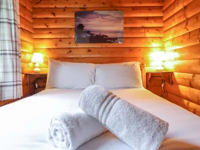 a bedroom with a bed with towels on it at Y Bwthyn Pren, Cabin 209, in Trawsfynydd