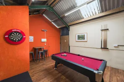a pool table in a room with an orange wall at Ty Cefn by Birch Stays in Llangyniew