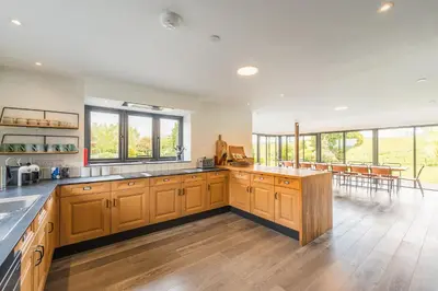 a large kitchen with wooden cabinets and windows at Ty Cefn by Birch Stays in Llangyniew