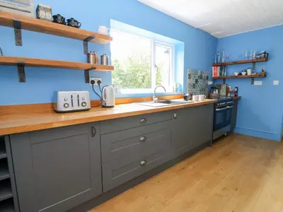 a kitchen with blue walls and a counter with a sink at The Old Barn in Lampeter