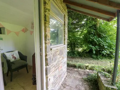an open door of a house with a window and a chair at The Old Barn in Lampeter