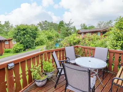 a patio with a table and chairs on a deck at Swn Yr Afon - No 333 in Trawsfynydd