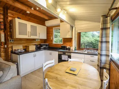 a kitchen and dining room with a wooden table at Swn Yr Afon - No 333 in Trawsfynydd