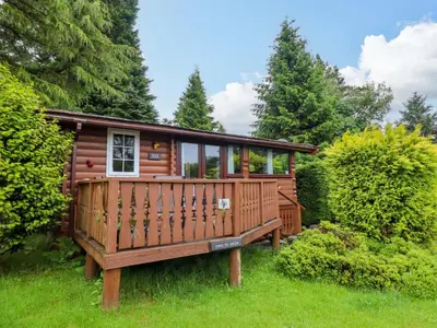 a cabin in the woods with a large deck at Swn Yr Afon - No 333 in Trawsfynydd