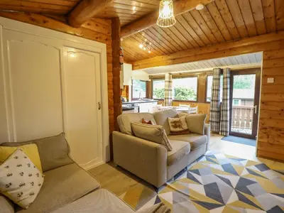 a living room with two couches and a kitchen at Swn Yr Afon - No 333 in Trawsfynydd