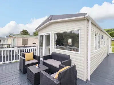 a tiny house with two chairs and a table on a deck at 8 Puffin Way in Llwyngwril