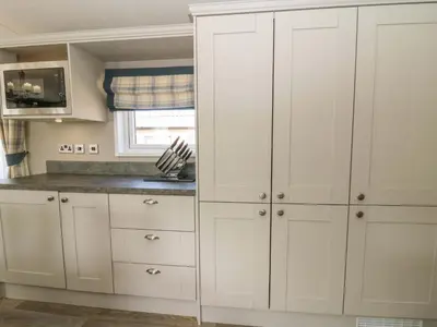a kitchen with white cabinets and a window at 34 The Beaumont in New Quay