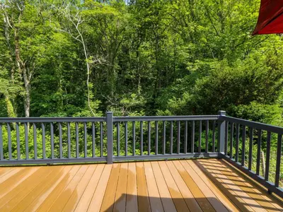a wooden deck with a black railing and trees at 34 The Beaumont in New Quay