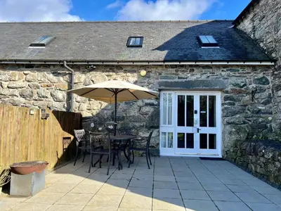 a table with an umbrella in front of a stone building at One-Bedroom Cottage in Snowdonia National Park in Dolgellau